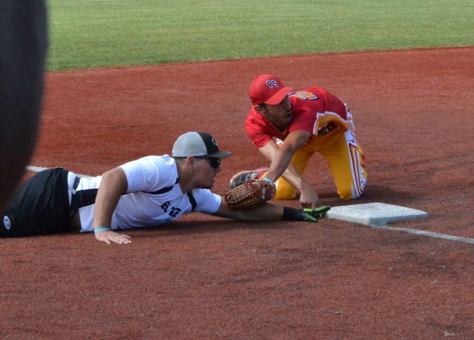 Baseball player in red tags out runner sliding into home plate during a close play