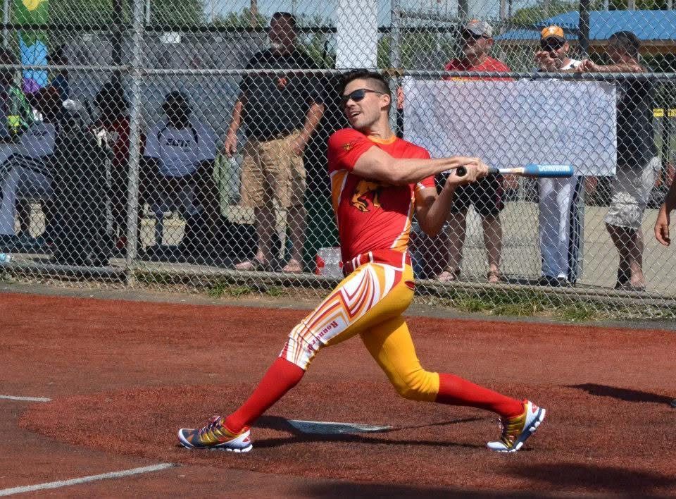 Athlete in red and yellow throws a javelin on a track field, with spectators behind a fence.
