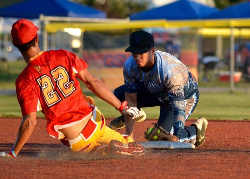 Baseball player in red sliding into base as fielder in blue reaches to tag him out