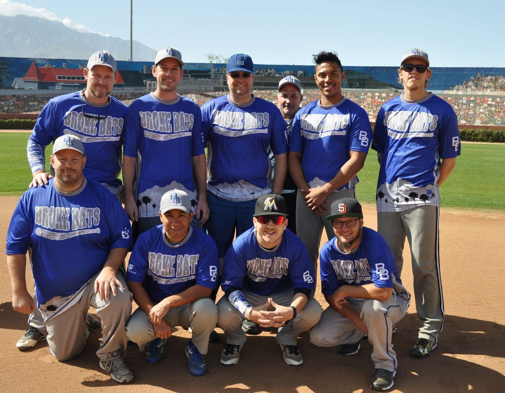 Baseball team in blue jerseys posing on a dirt field with mountains in the background