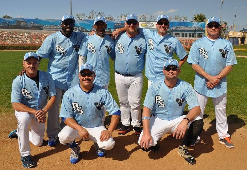 Baseball team in light blue uniforms posing on a field with stadium seating in the background