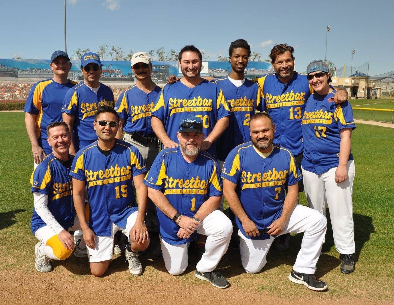 Youth baseball team in blue jerseys posing together on a field under a clear sky
