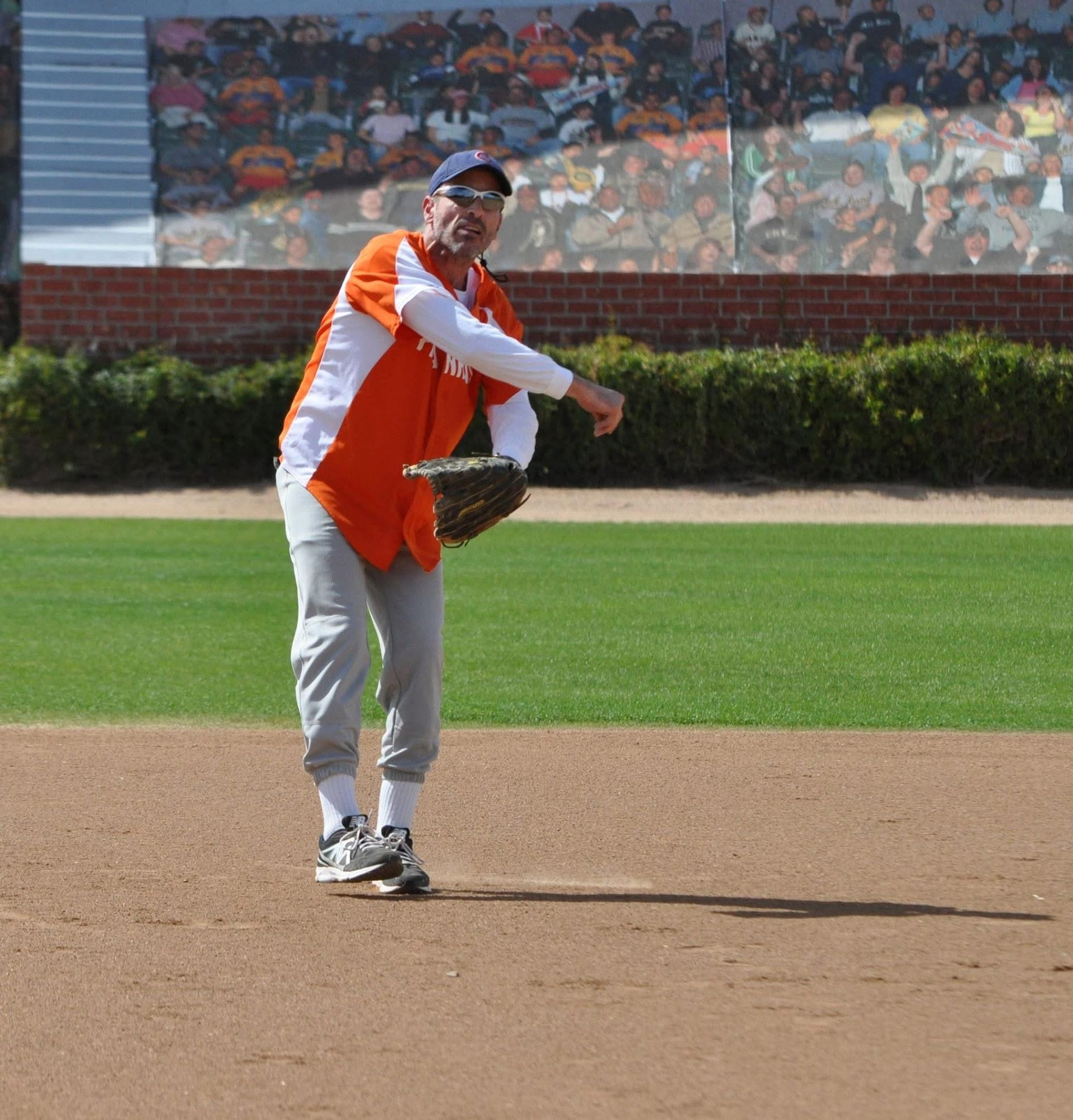 Baseball player in orange and white uniform throwing a ball on the field