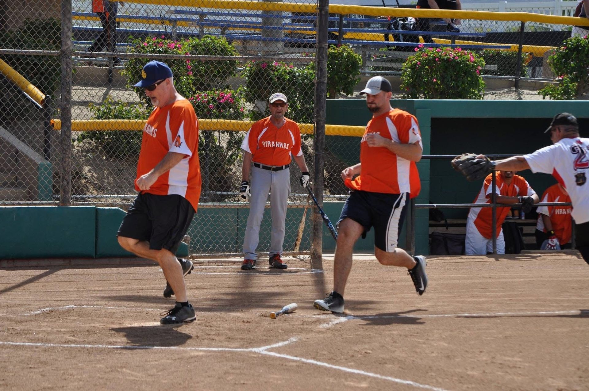 Baseball players in orange uniforms running on a dirt field during a game