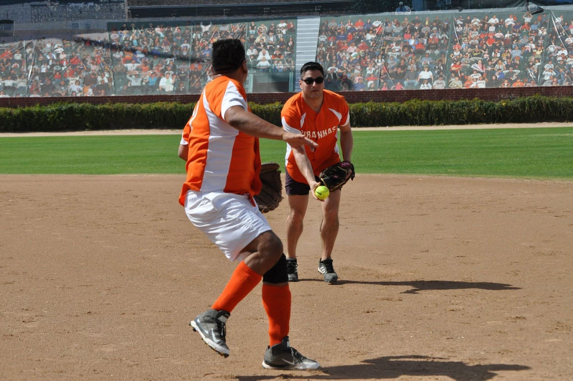 Two baseball players in orange uniforms celebrate on the infield during a game.