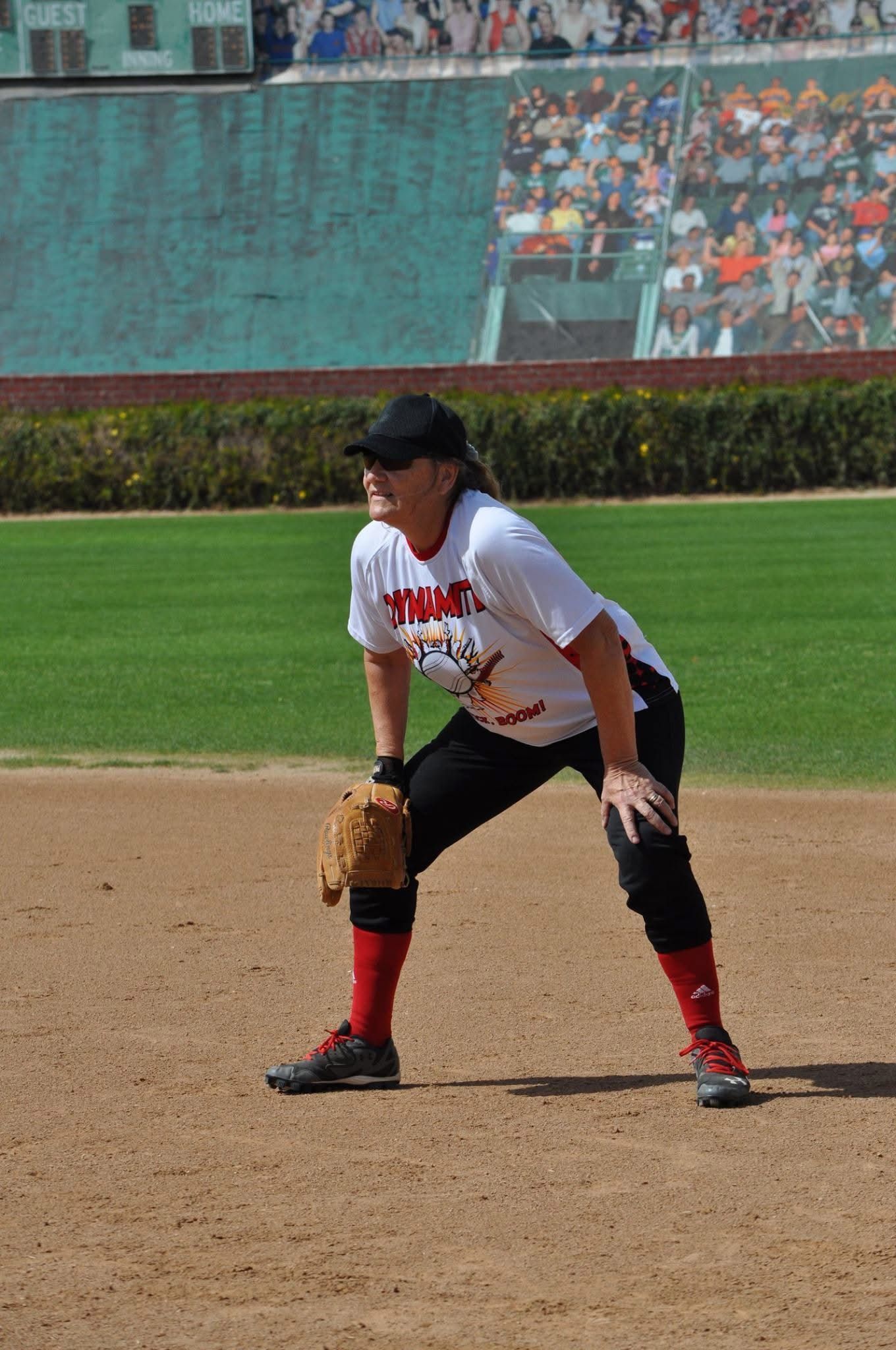 Baseball player in white and black uniform crouching on infield dirt, ready to field a ball.