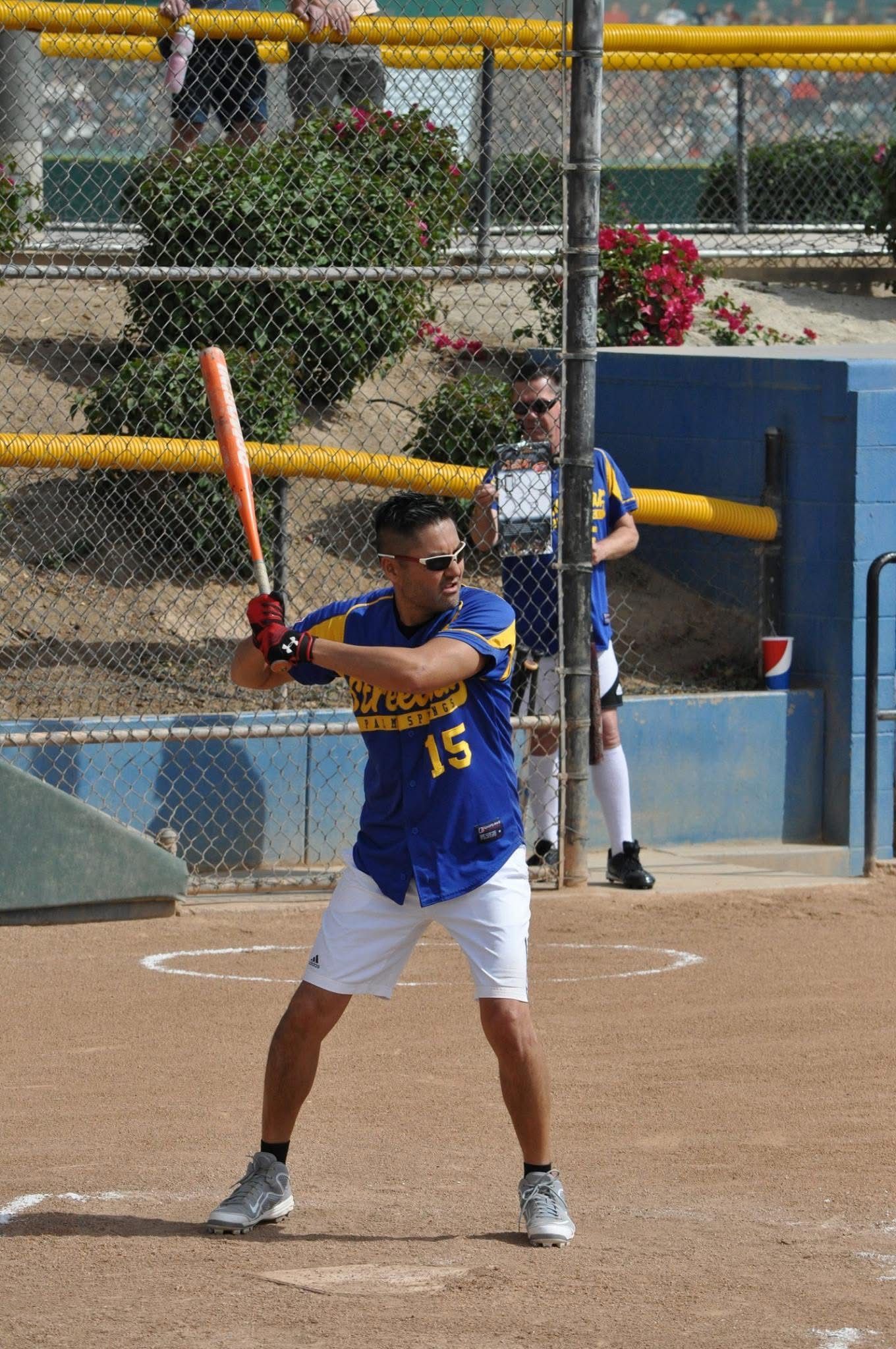 Softball batter in blue jersey swings at a pitch on a dirt field, catcher visible behind her.