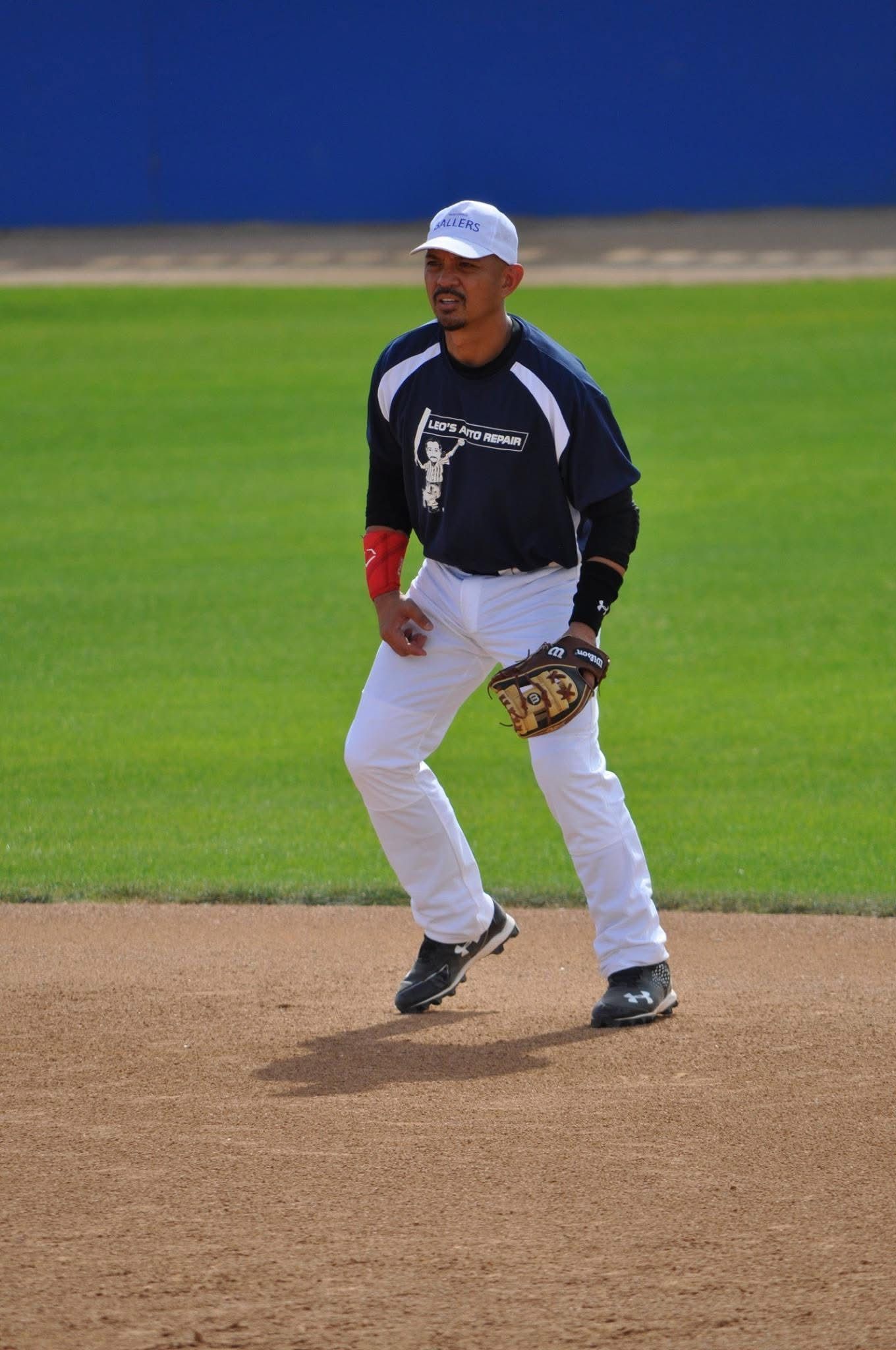 Baseball player in black and white uniform standing on the field with a glove, ready to field.
