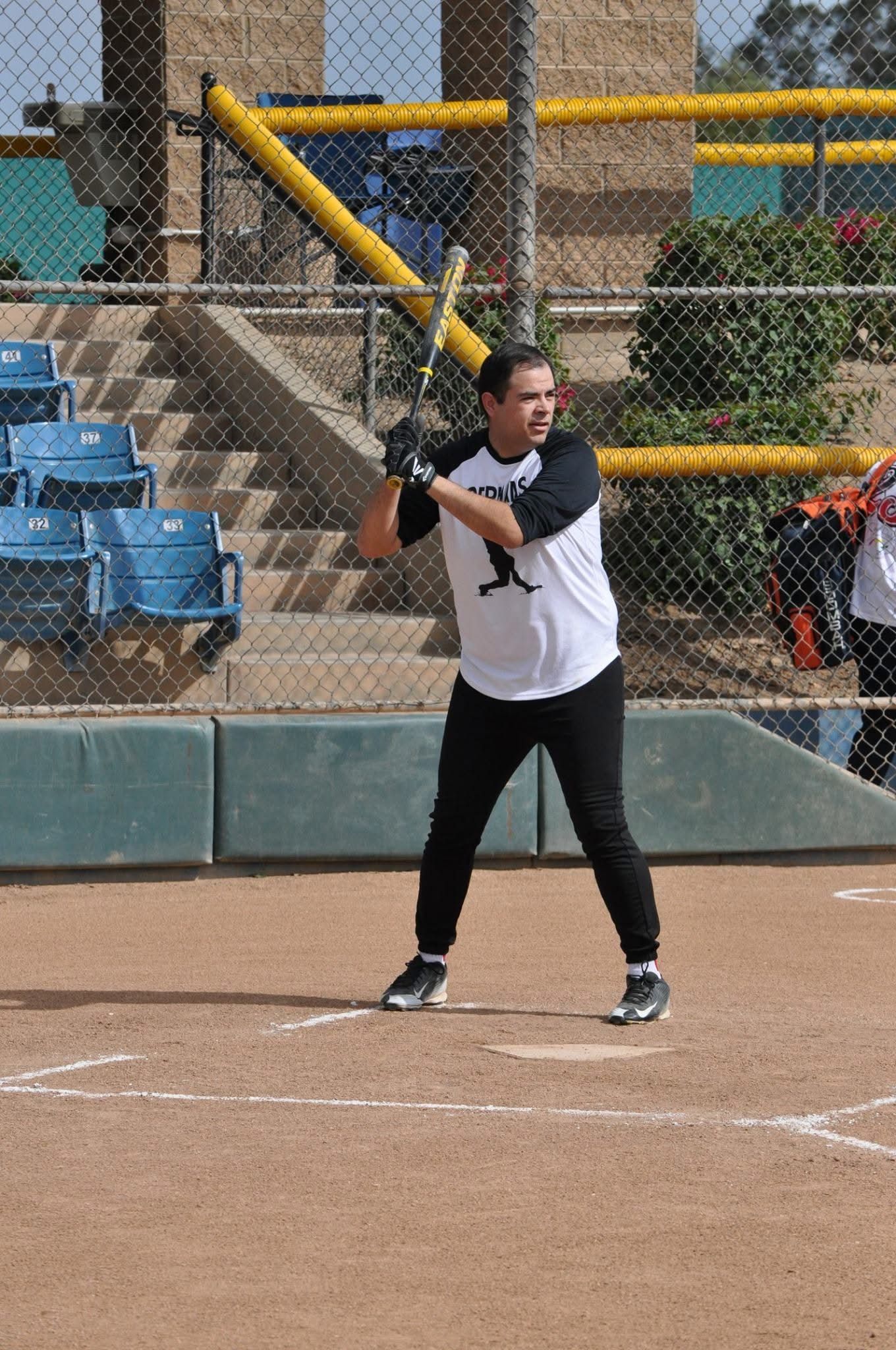 Softball batter in black and white at the plate, holding a yellow bat on a dirt field.
