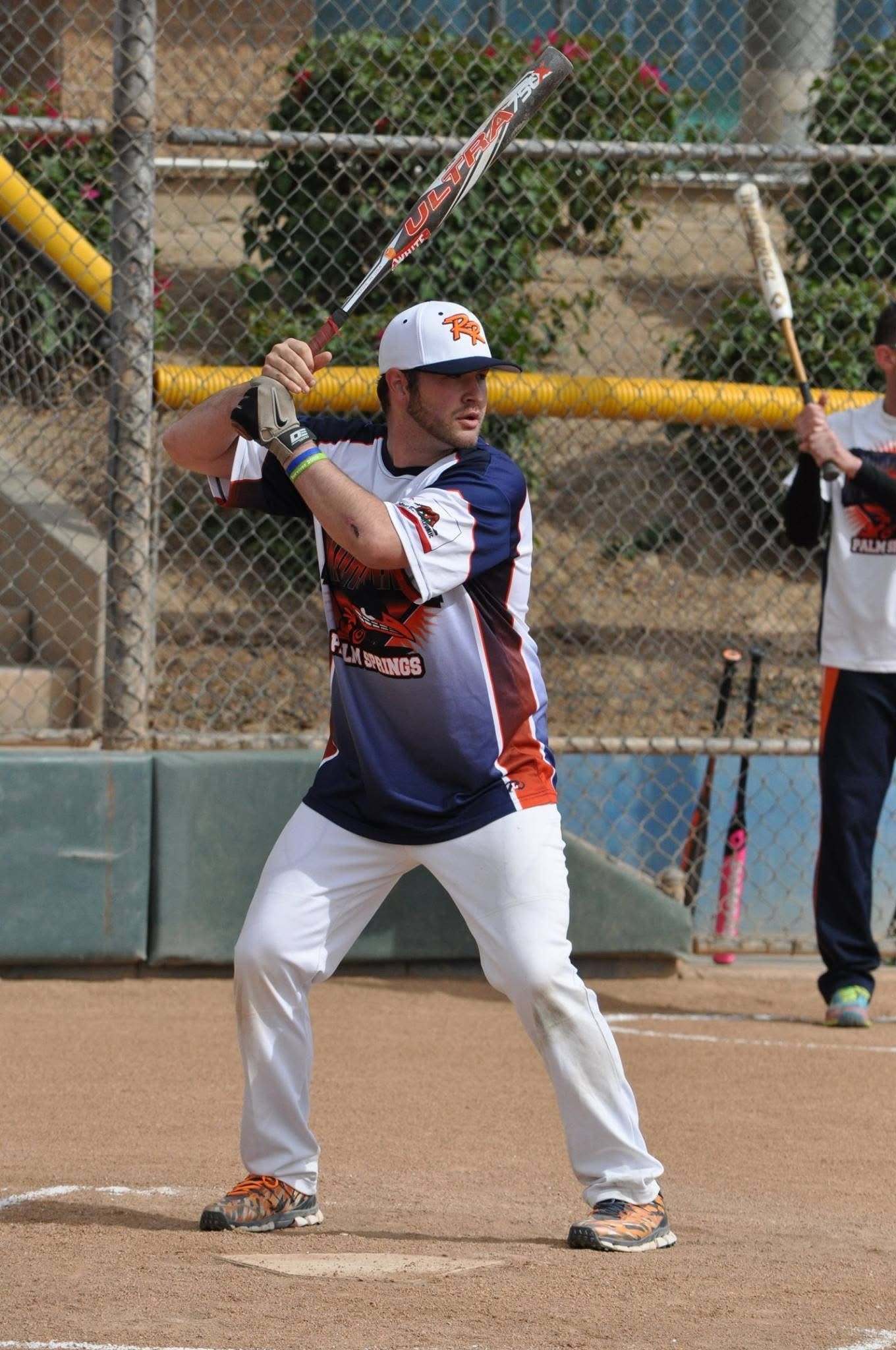 Baseball player in navy and white uniform holding a bat at home plate on a dirt field