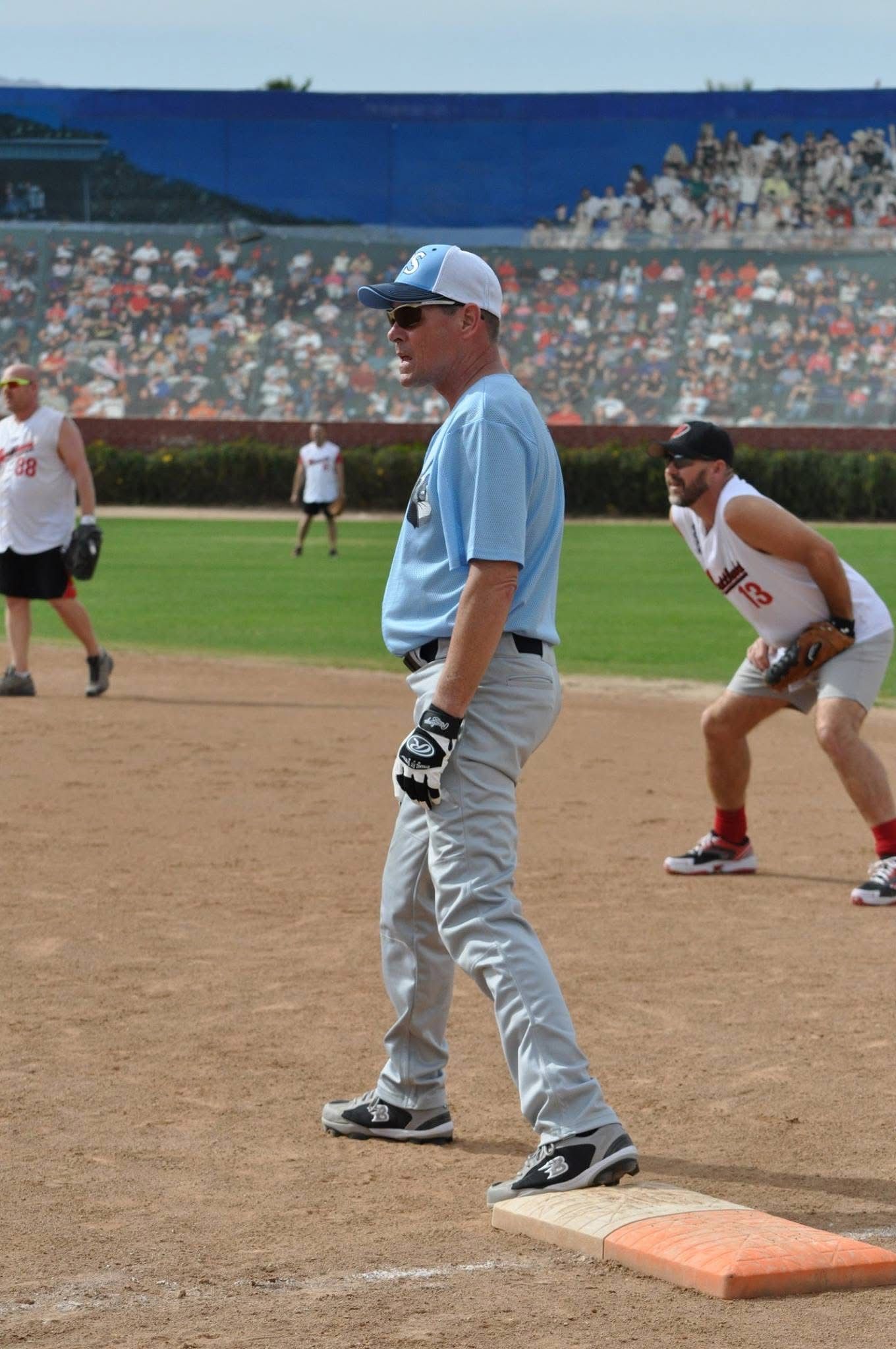 Baseball player in light blue uniform standing on first base during a game