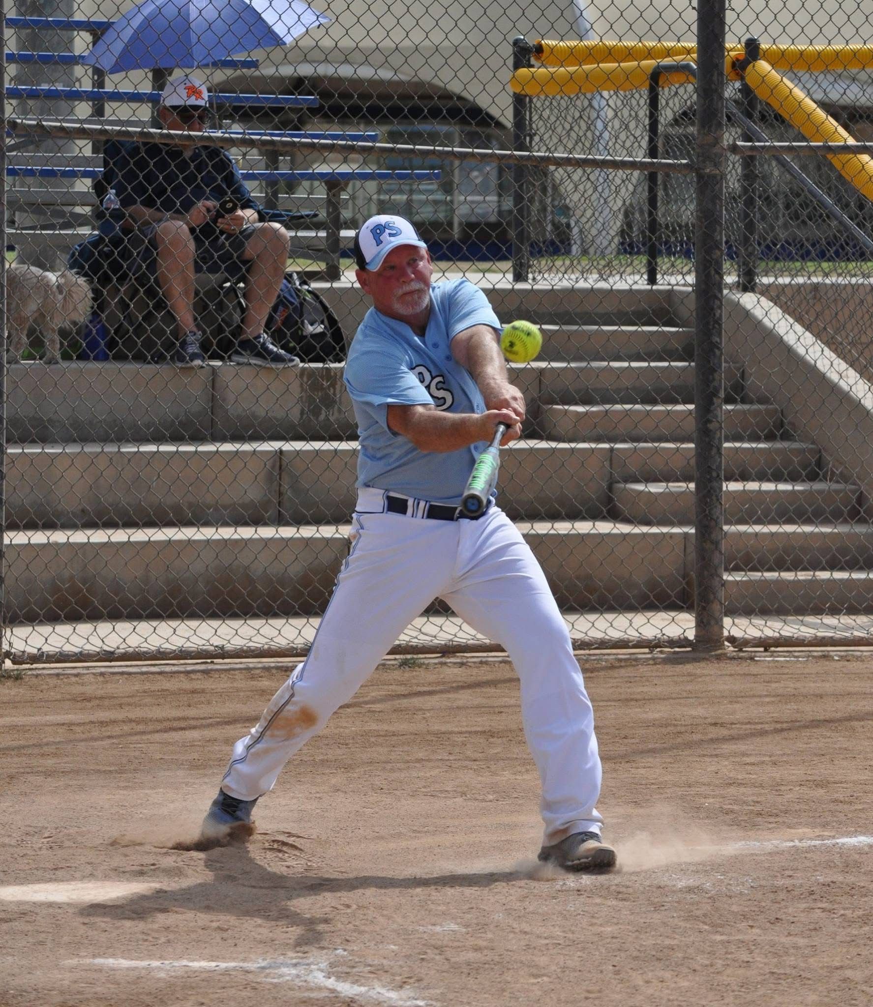 Baseball batter in light blue uniform swinging at a pitch on a dirt field.