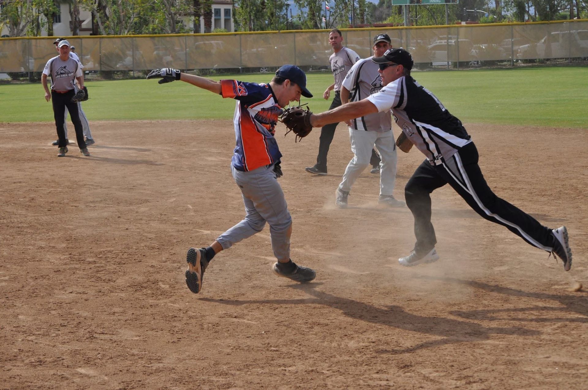 Two baseball players collide at home plate as dust rises during a play on a dirt field.