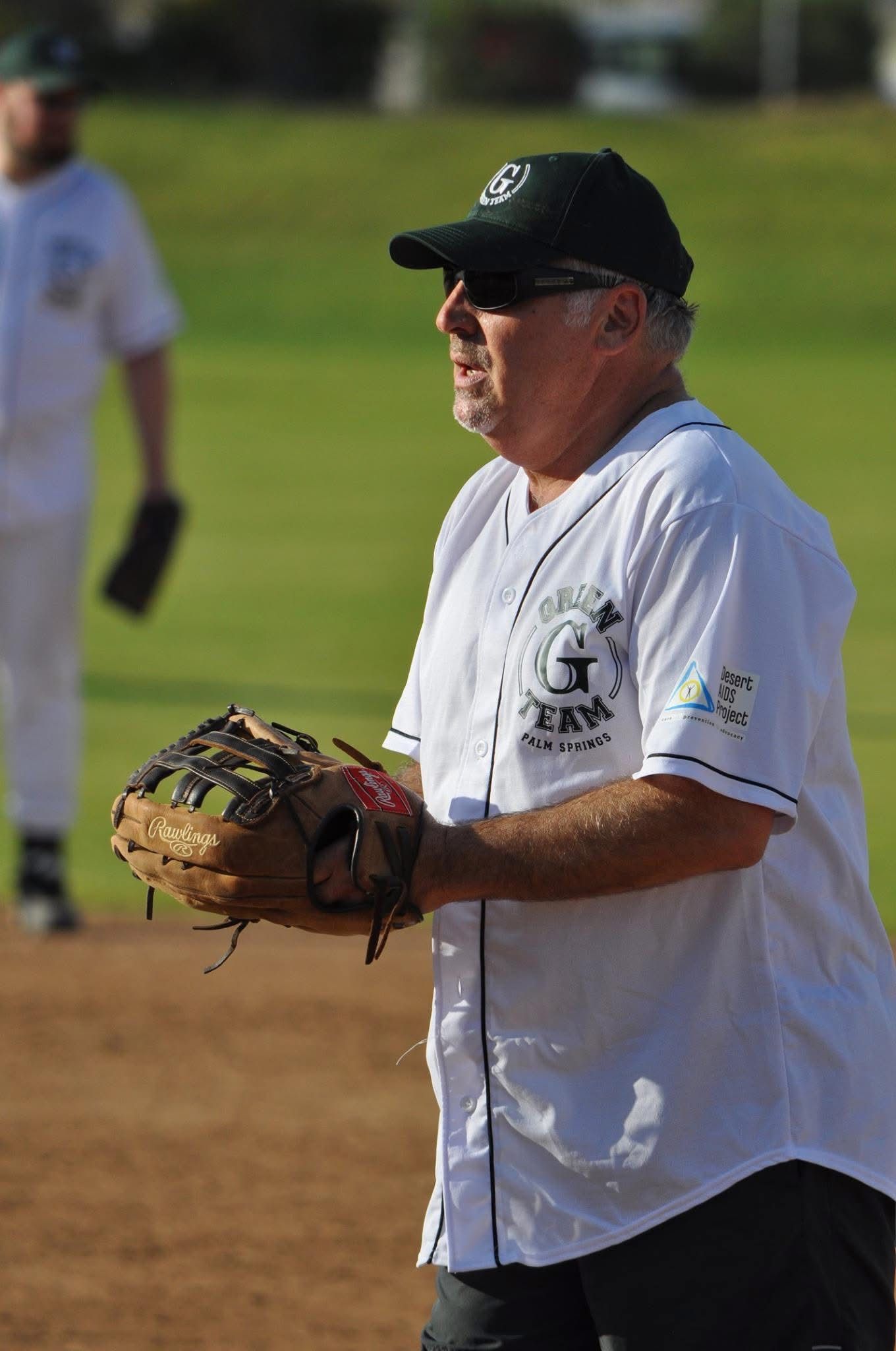 Baseball player in white jersey and black cap holding a glove on a field