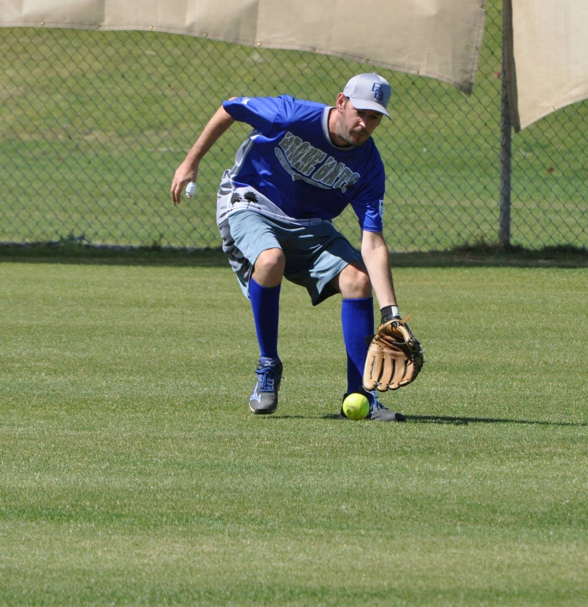 Baseball player in blue uniform fielding a ground ball on grass field
