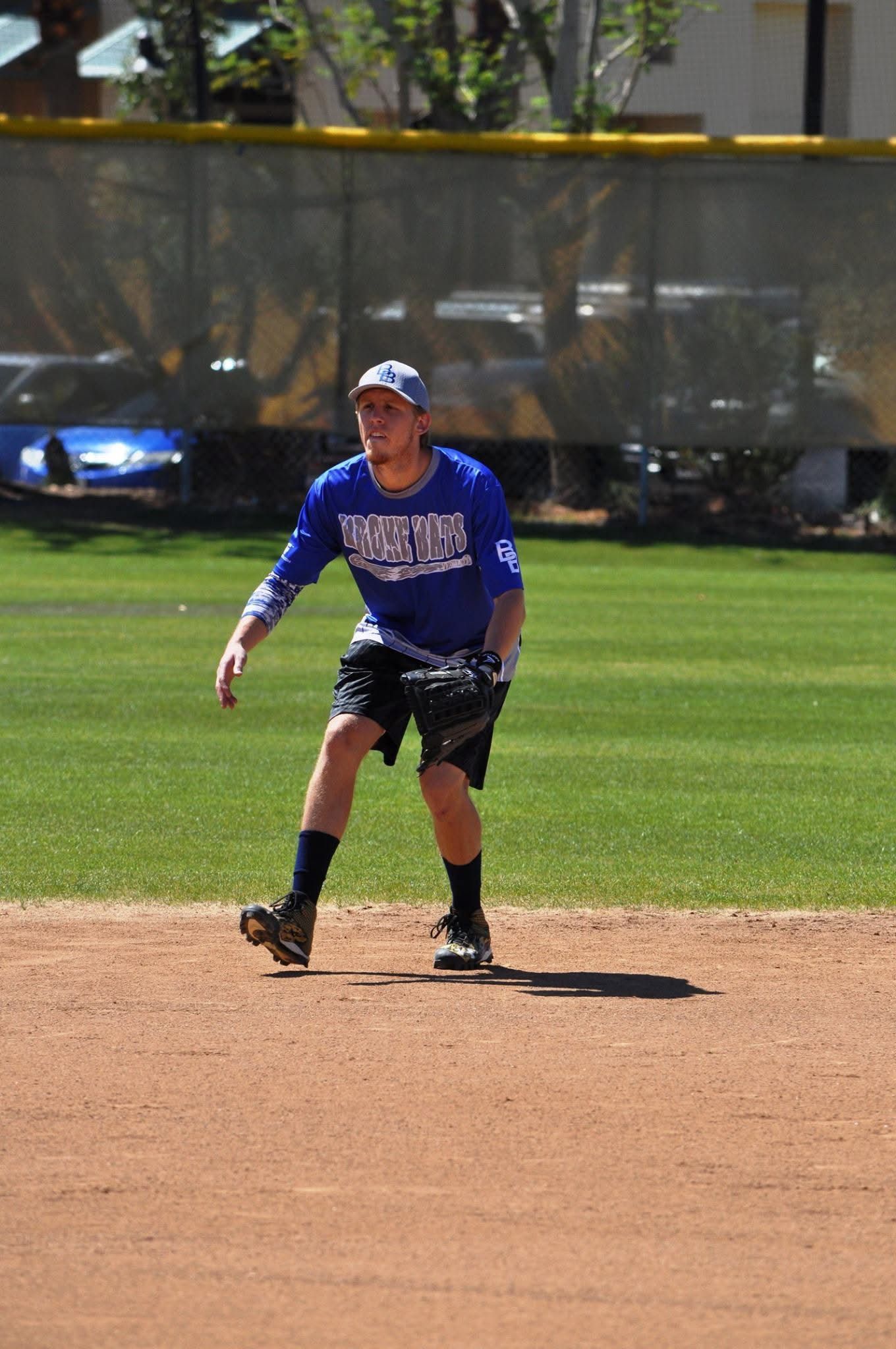 Baseball player in blue uniform stands on the infield dirt during a game.