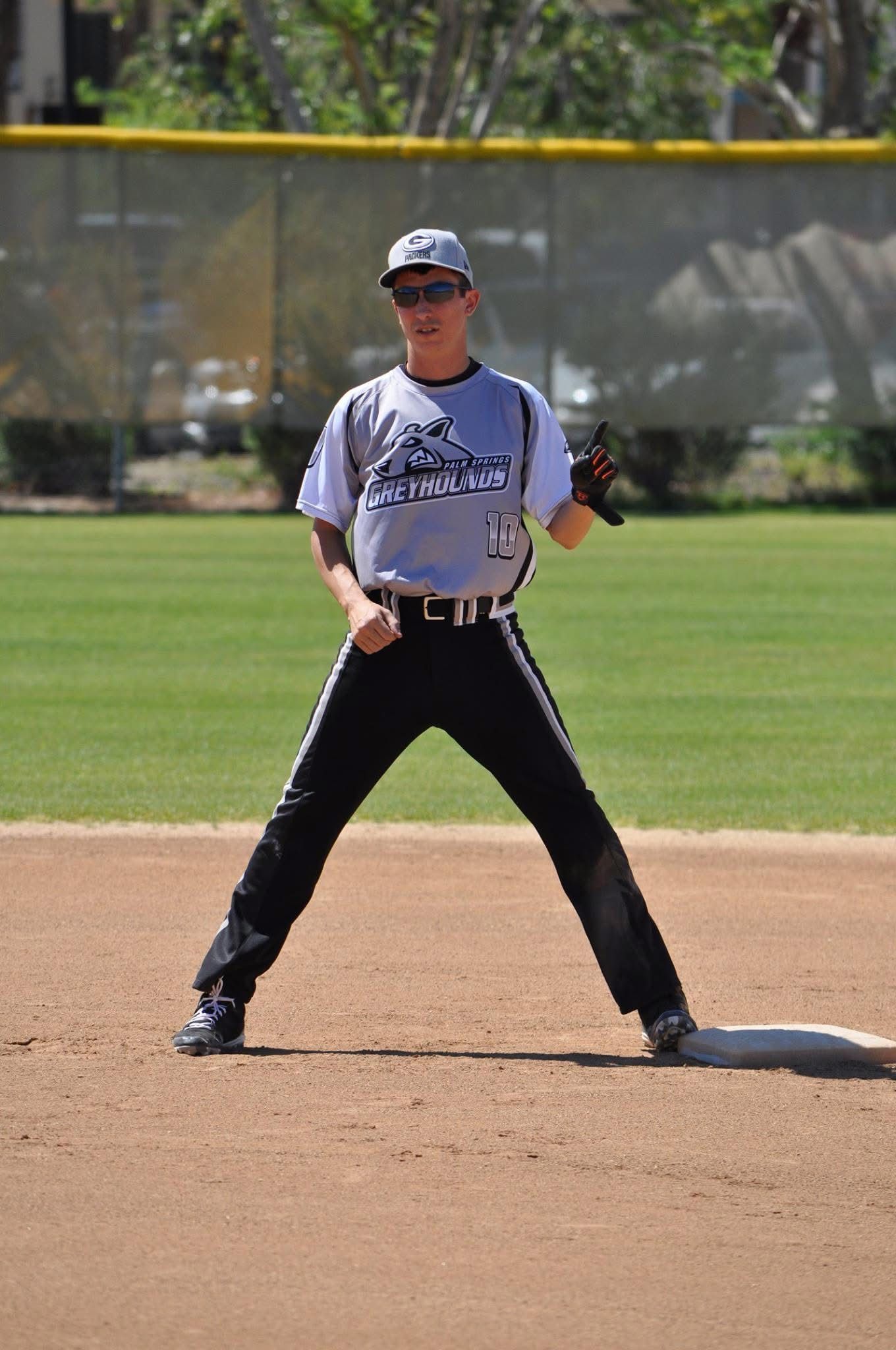Baseball player in gray uniform stands on infield dirt, holding a glove during a game.