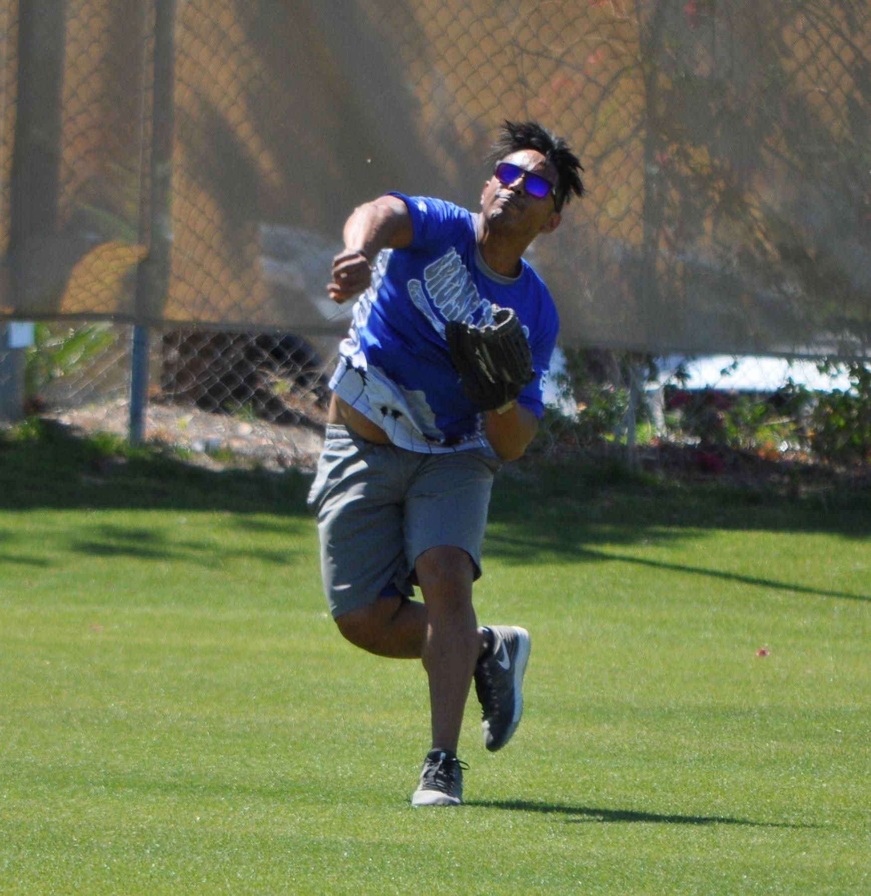 Person in blue shirt and gray shorts catching a ball on a grassy field