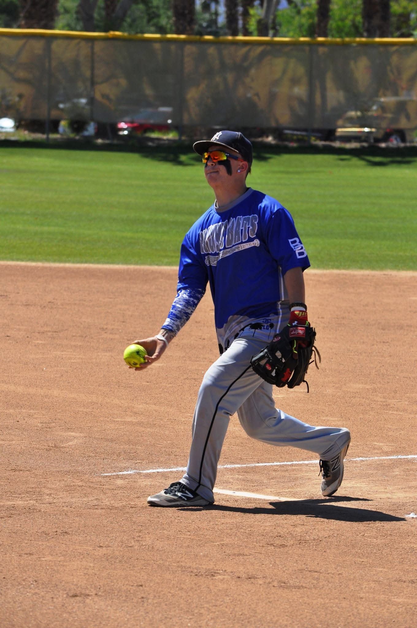 Baseball pitcher in blue uniform holding a ball on the infield, preparing to throw