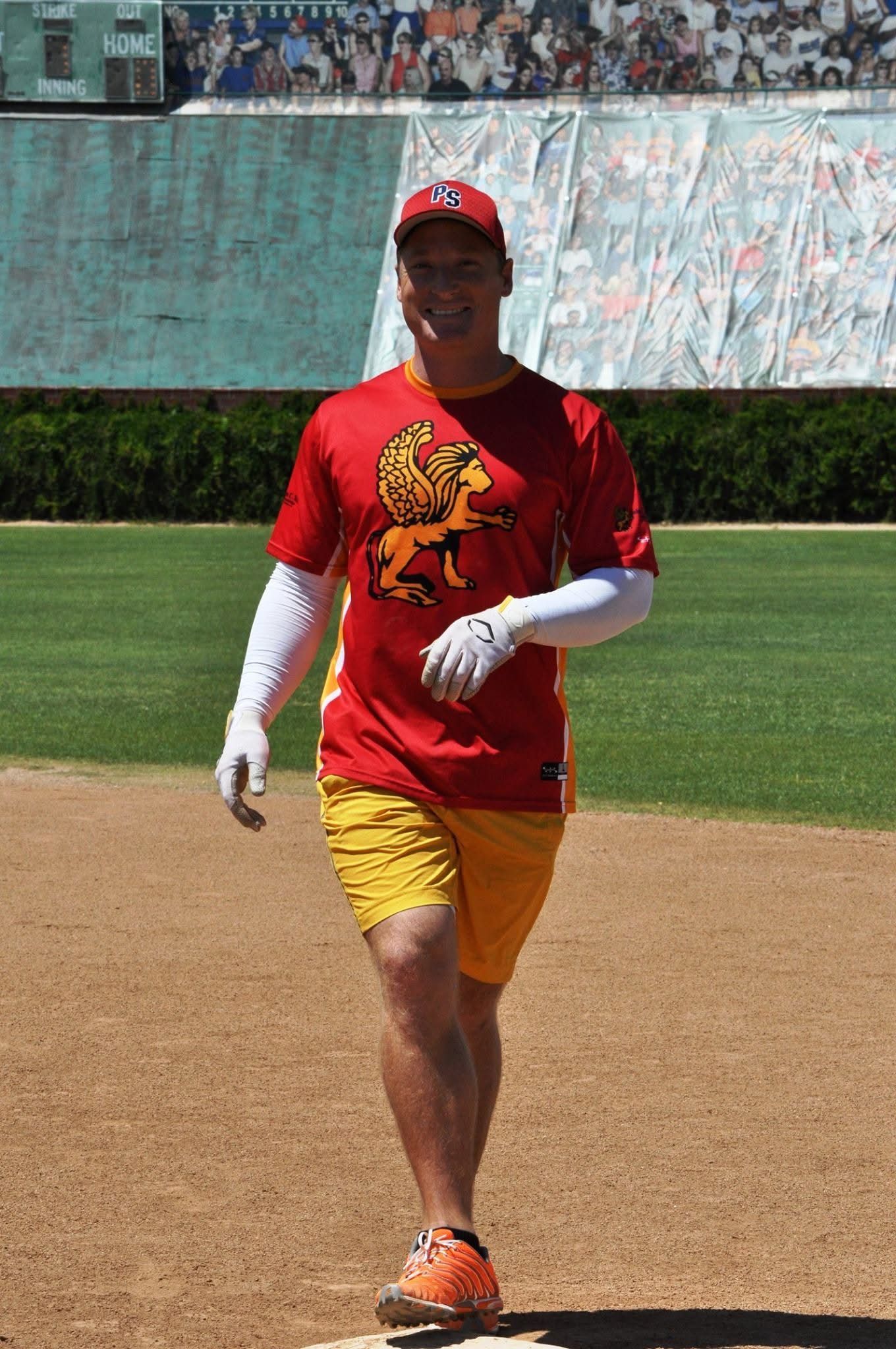 Baseball player in red shirt and yellow shorts walking on a field during practice