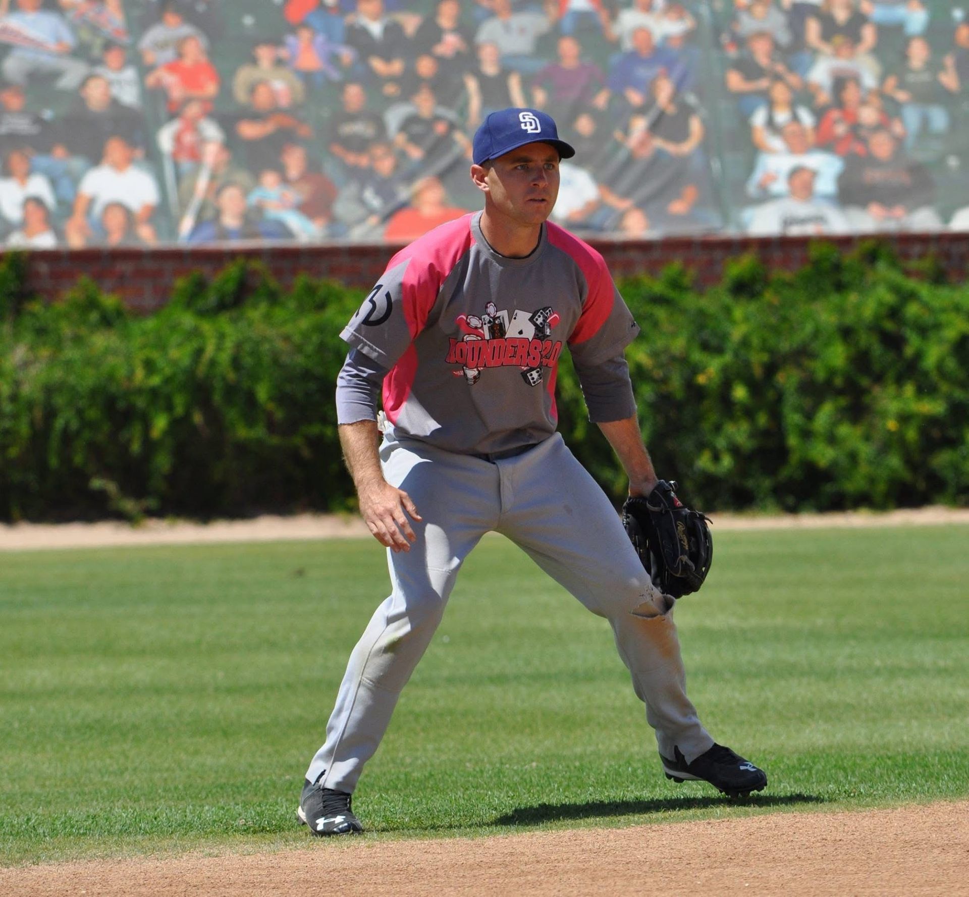 Baseball player in gray and pink uniform ready in the outfield on a sunny field