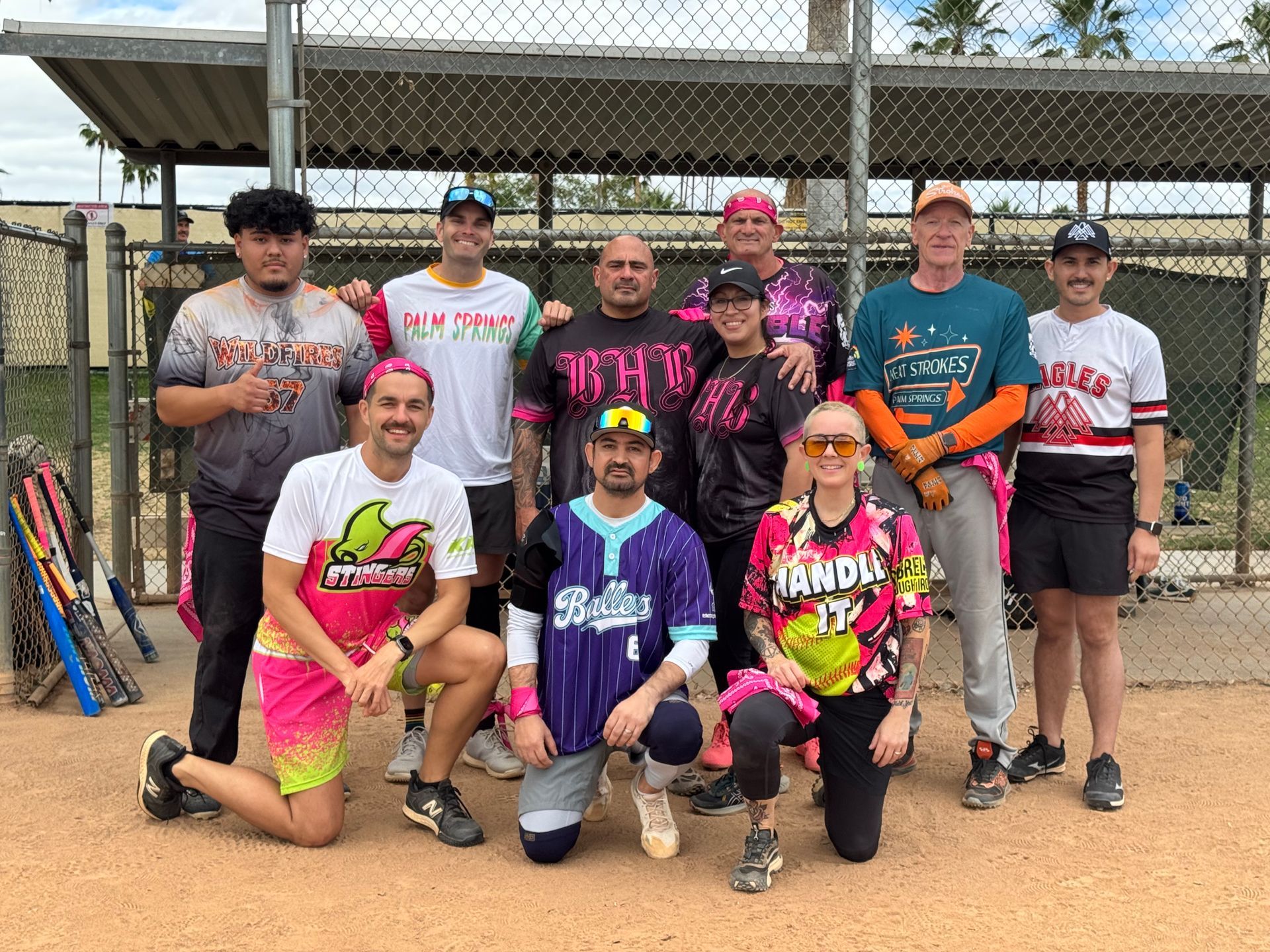Group of athletes posing with paddles and race gear on a dirt field, smiling after an event