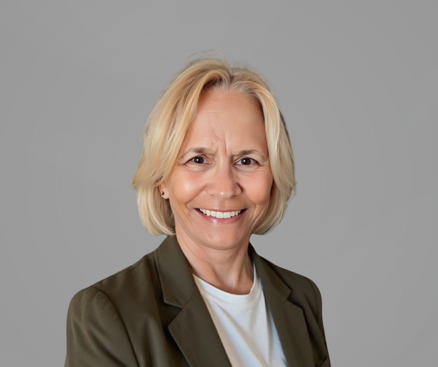 A headshot of Vicky Harrison, a woman smiling, wearing a blazer, set against a solid gray background.