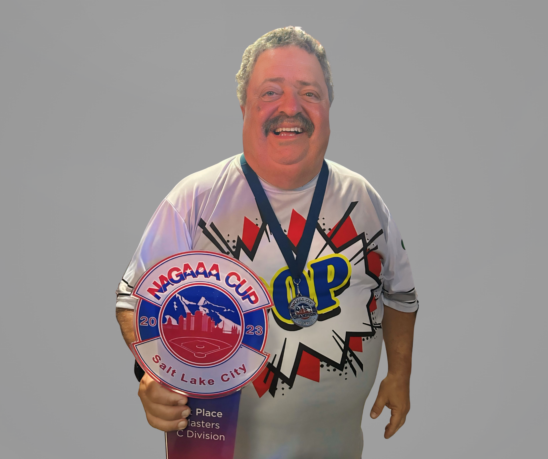 Smiling man holding a medal and award plaque against a plain gray background