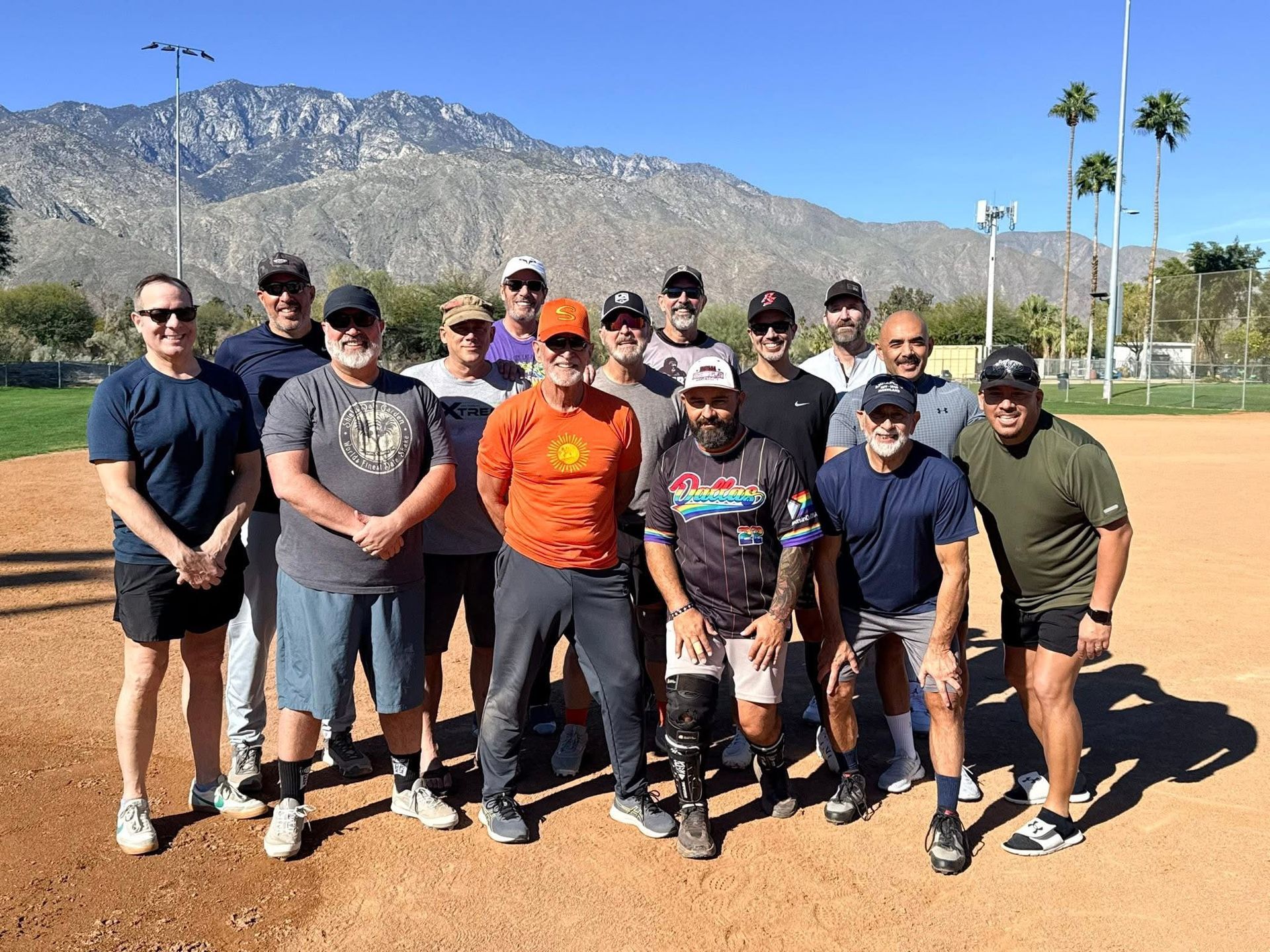 Group of baseball players posing on a dirt field with mountains in the background