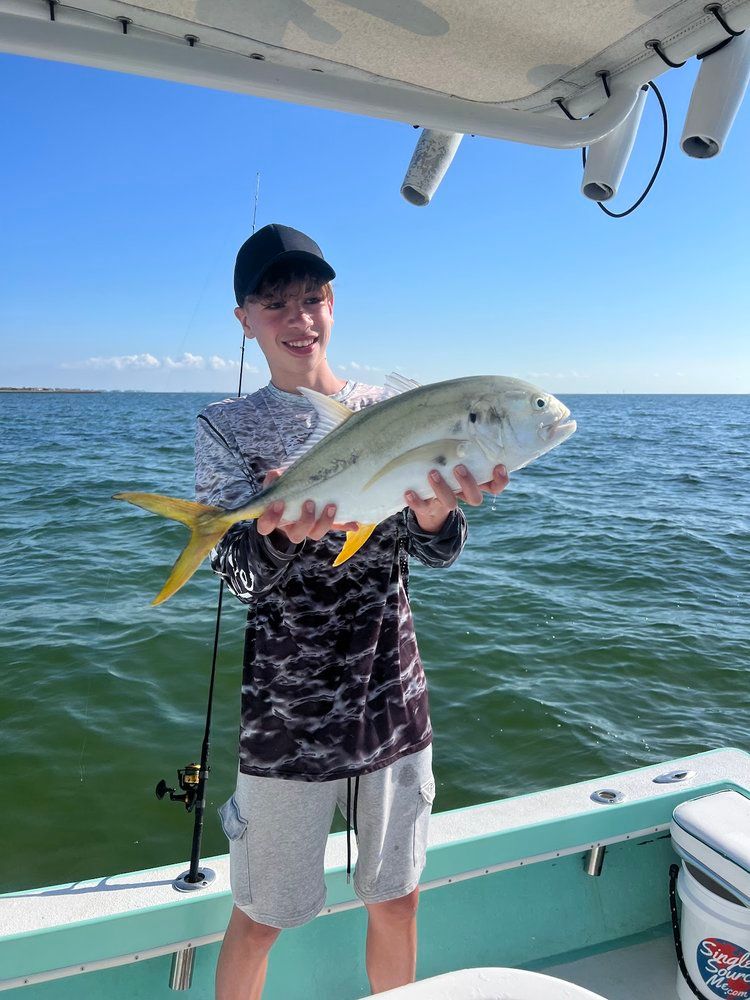 A young boy is holding a fish on a boat.
