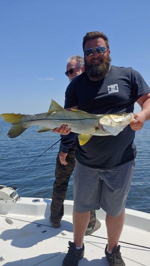 A man with a beard is holding a large fish on a boat.
