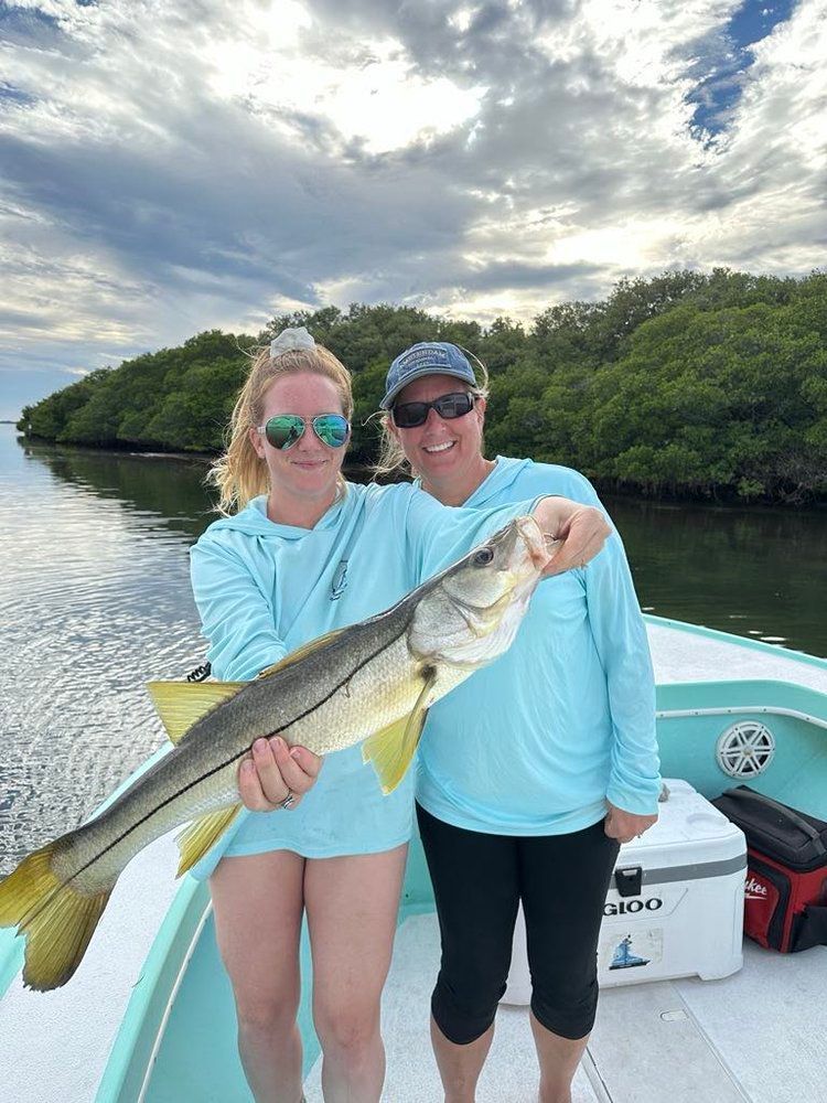 Two women are holding a large fish on a boat.