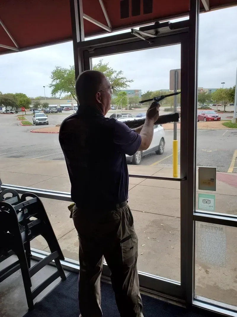 A man is cleaning a window with a brush.