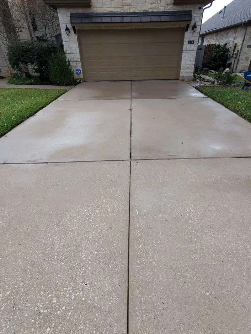 A concrete driveway in front of a house with a garage door.