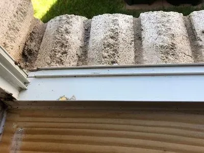 A close up of a window sill with a roof in the background.