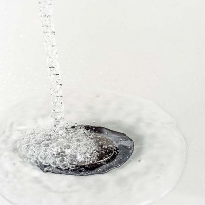 Water is running down a drain in a bathroom sink.