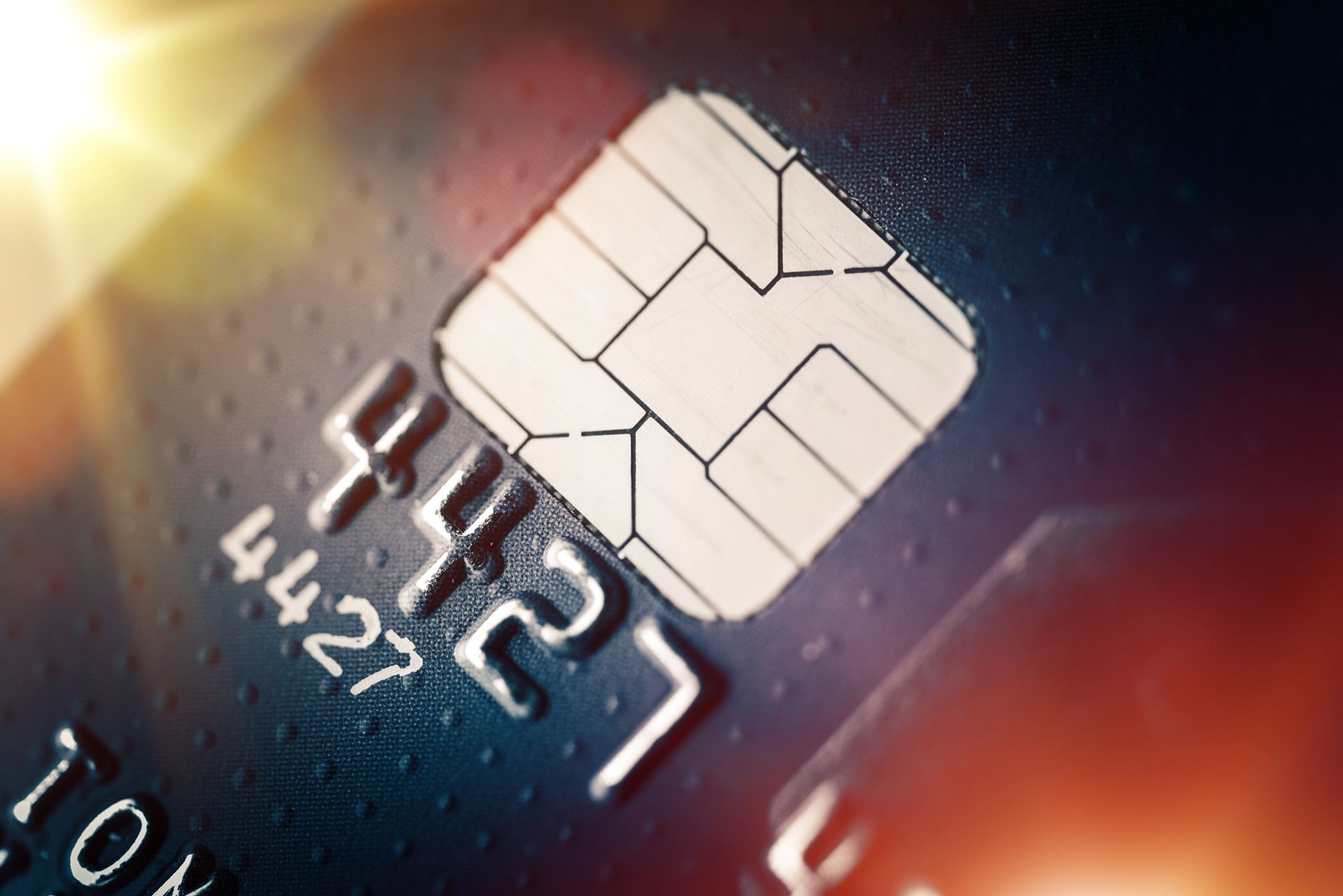 Close-up of a blue credit card with a microchip and visible numbers, reflecting bright light. Close-up of a blue credit card with a microchip and visible numbers, reflecting bright light.
