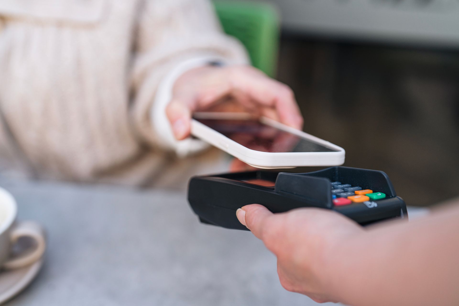 Person paying with phone held over a point-of-sale terminal. Person paying with phone held over a point-of-sale terminal.