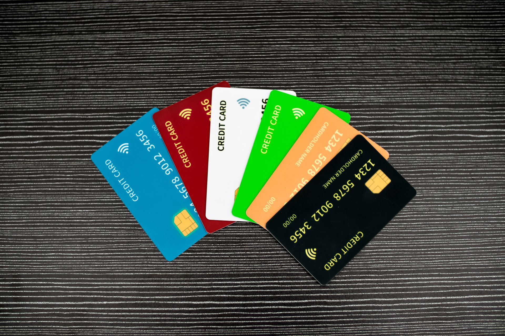 Pile of colorful credit cards fanned out on a dark wooden surface, showcasing various designs and logos. Pile of colorful credit cards fanned out on a dark wooden surface, showcasing various designs and logos.