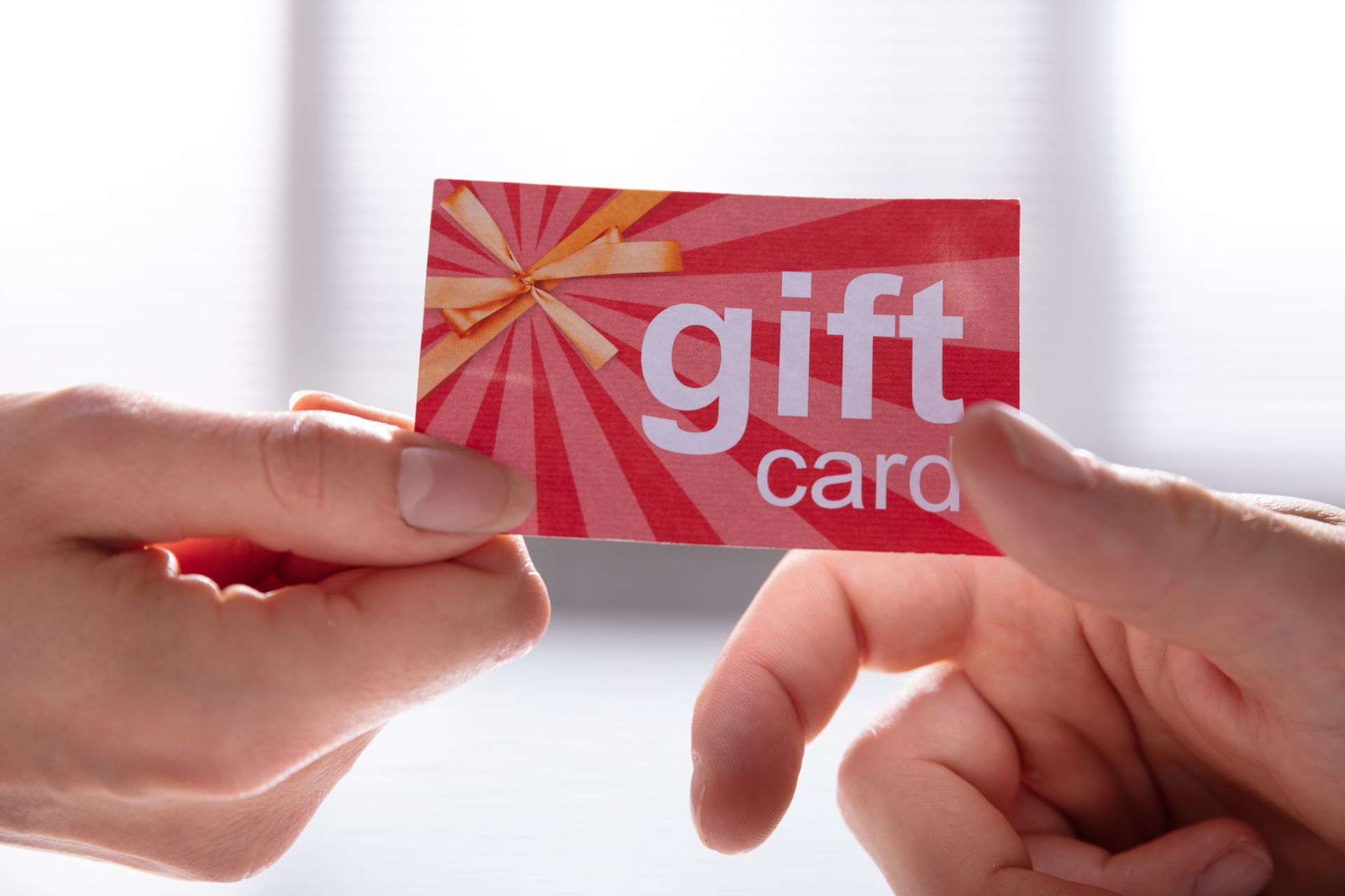 Two hands holding a red and orange gift card with Two hands holding a red and orange gift card with