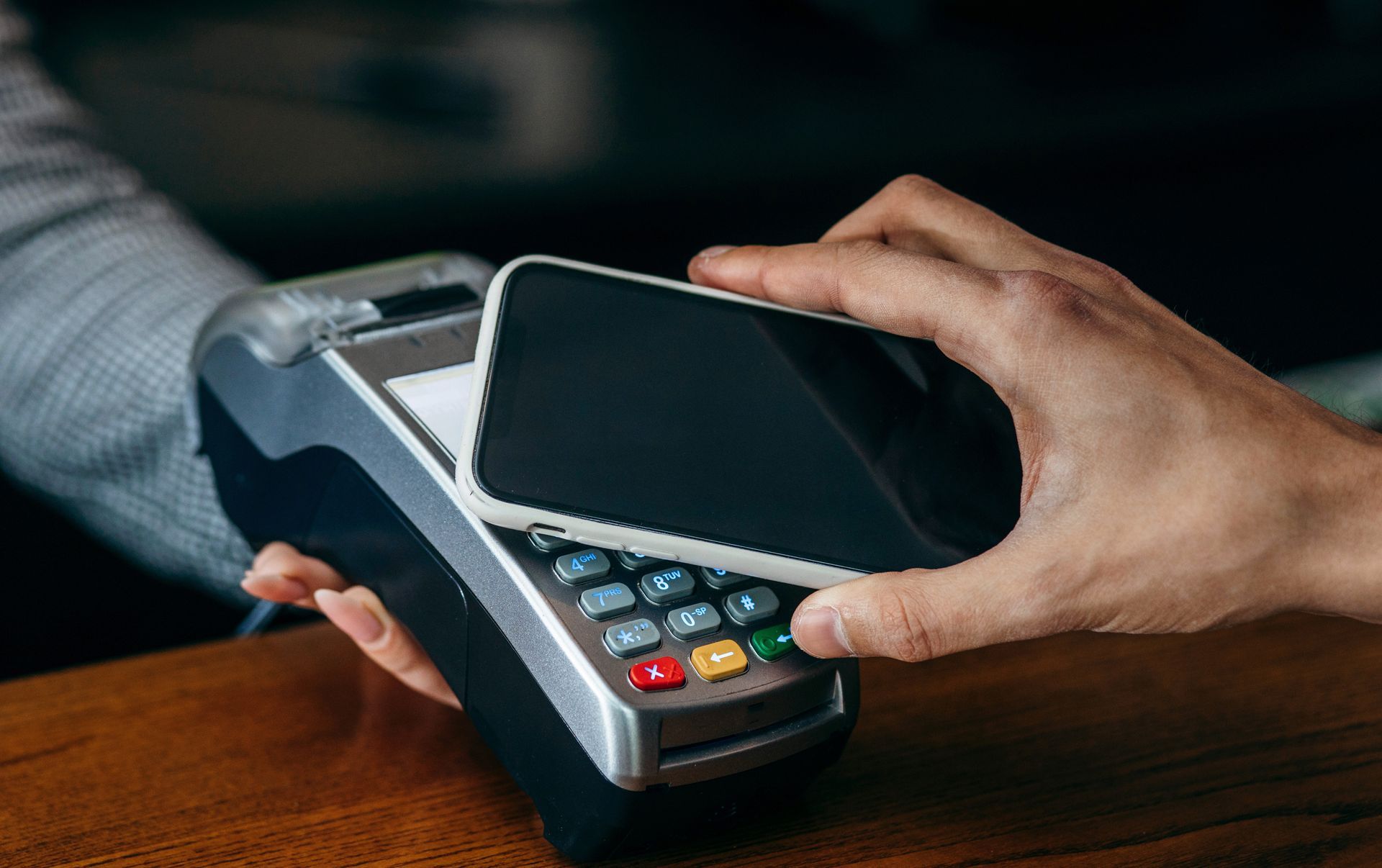 Smartphone held over a point-of-sale device for contactless payment. Smartphone held over a point-of-sale device for contactless payment.
