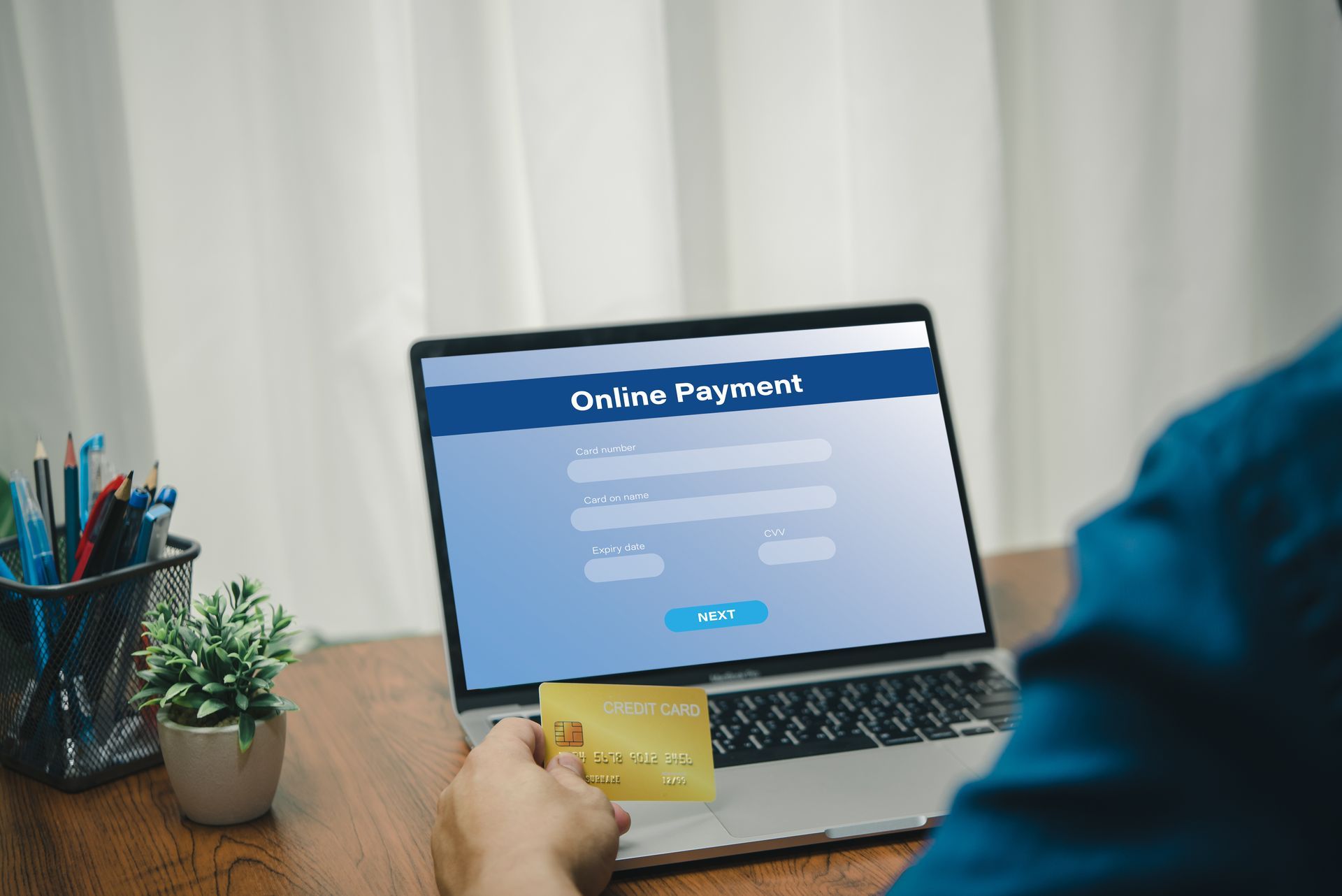 Person using a laptop to make an online payment with a gold credit card. Person using a laptop to make an online payment with a gold credit card.
