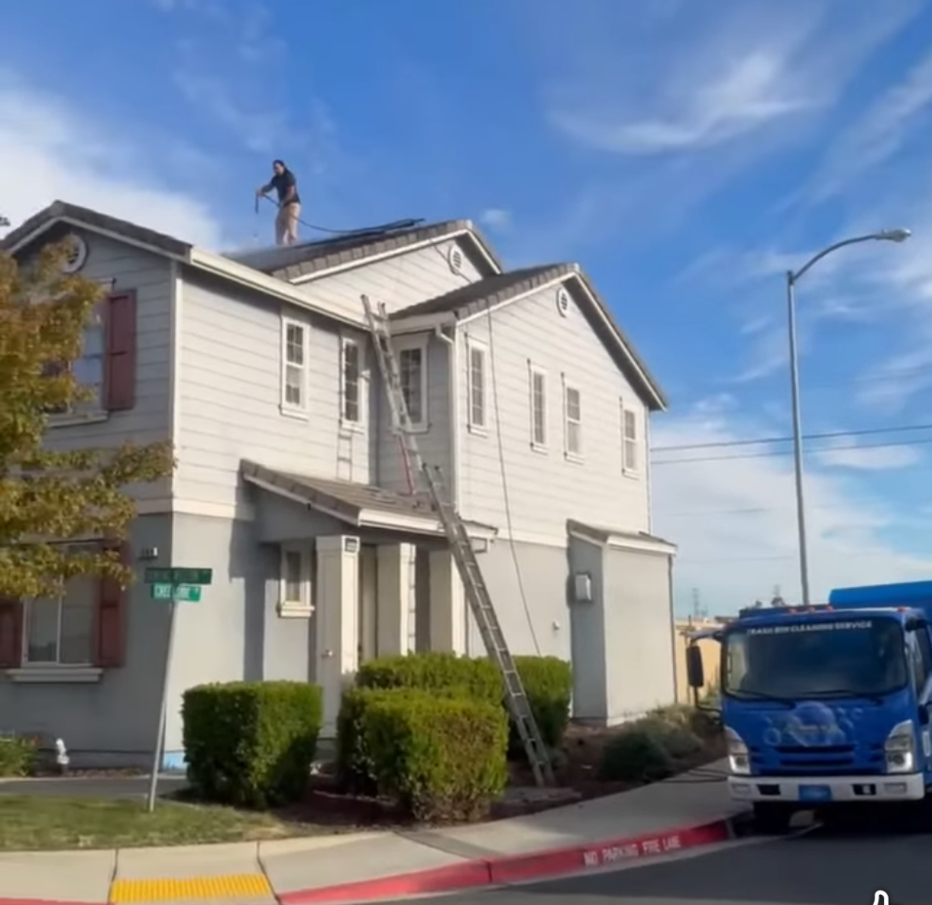Technician on the roof of a two-story Pittsburg home during solar panel cleaning.