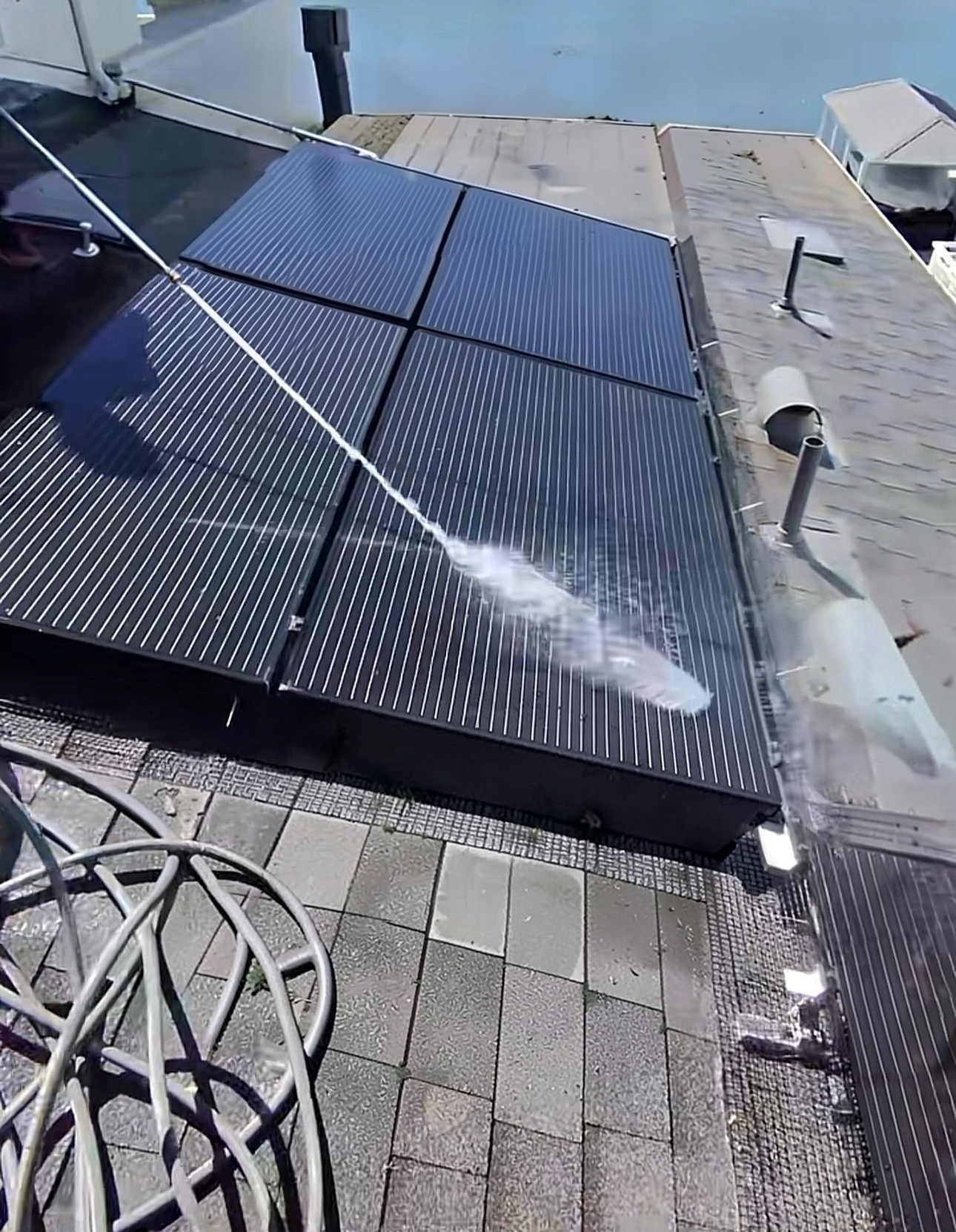 Rooftop solar panels being rinsed with water during cleaning in Bethel Island