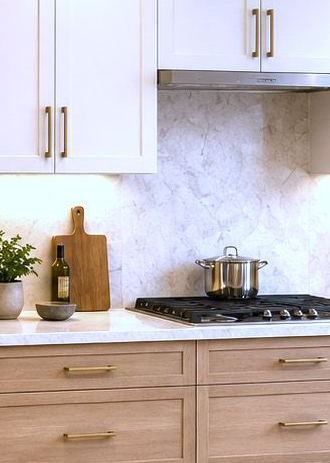 Modern kitchen with white cabinets, marble backsplash, and a pot on the gas stovetop