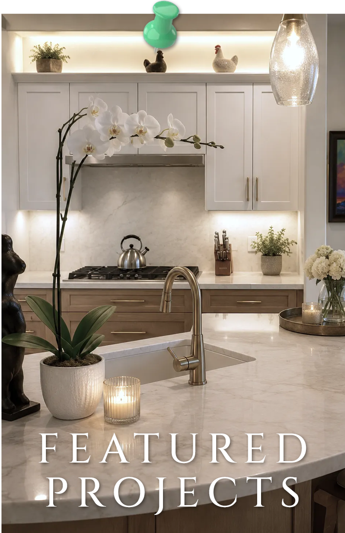 Modern kitchen with marble island, white cabinets, orchids, pendant light, and a lit candle on the counter