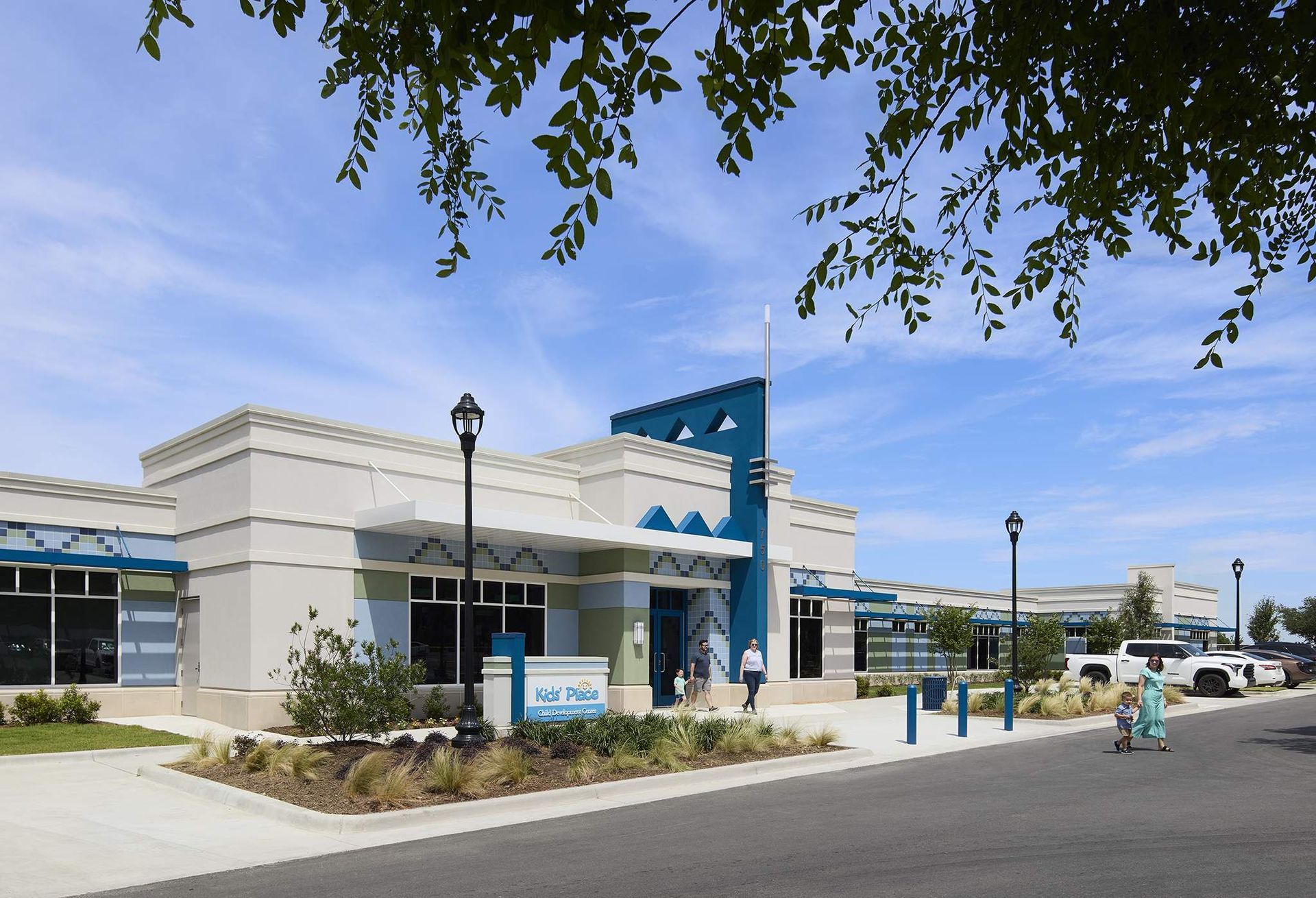 Modern white building with blue accents and a sidewalk under a clear sky
