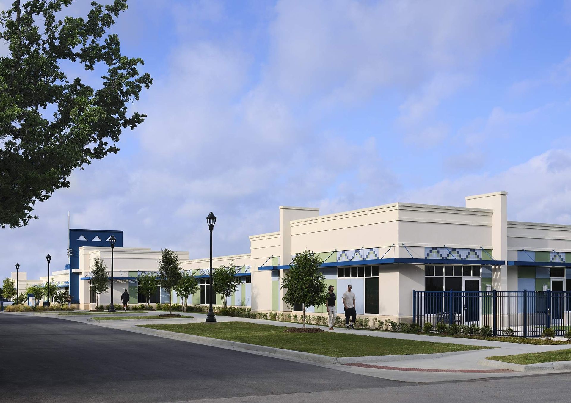 Modern building behind a fenced sidewalk and empty street under a blue sky