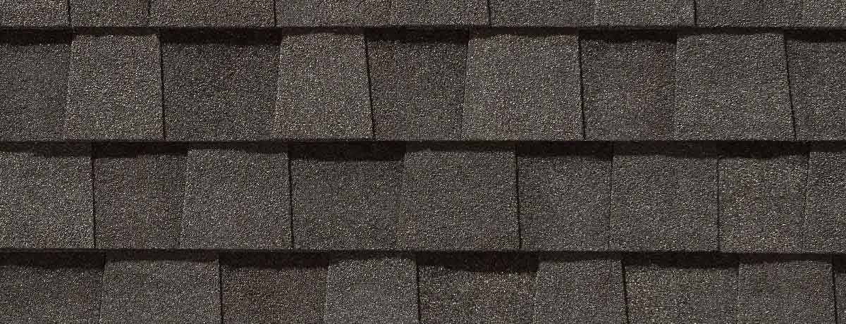 Close-up of dark gray asphalt roof shingles, overlapping in rows.