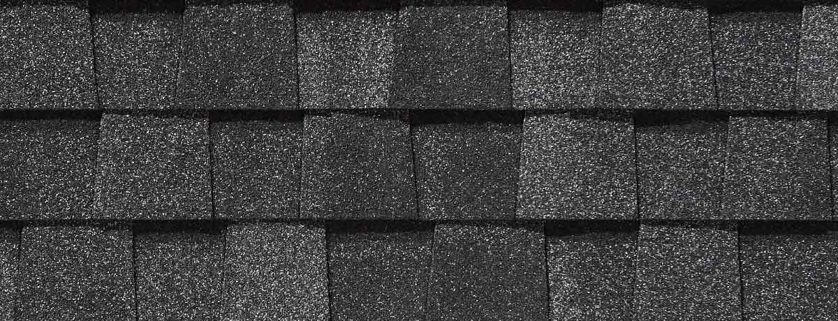 Close-up of black asphalt roof shingles in a layered pattern.